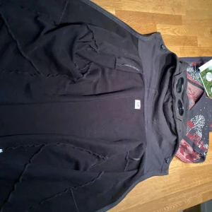 Svart zip hoodie från C.P. Company - Snygg svart zip hoodie från C.P. Company med hög krage och dragkedja. Perfekt för en stilren look. Jackan har en modern design med praktiska fickor och är tillverkad i ett slitstarkt material.