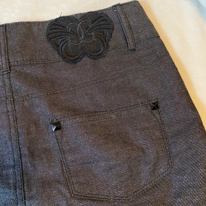 Grå glittrig vintage miniskirt - En glittrig miniskirt som är vintage i grå färg och är i jeans material med detaljer runt fickorna