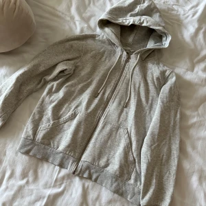 Grå hoodie med dragkedja - Säljer en grå hoodie i storlek S från H&M. Hoodien har en dragkedja framtill och en praktisk huva med snören och två fickor på framsidan. Skriv ifall du är intresserad!⭐️