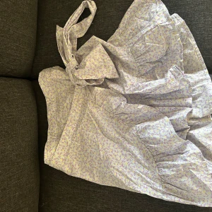 Blommig sommarklänning med volang - Säljer en superfin blommig kjol i ljusa färger, perfekt för sommaren! Den har en söt volangdetalj med knytband. Kjolen är i ett lätt och luftigt material, vilket gör den idealisk för varma dagar.