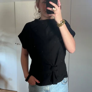 Svart topp med knytning - Säljer en svart topp från Zara med knytning framtill. Storlek M. Jättefint skick. Perfekt för fest och vardag🪩🖤💃