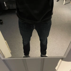 Nudie Jeans grim tim - Snygga mörkblå Nudie Jeans med ett bra skick, storlek 31/32, finns en liten slitning i grenen men det är den ända skadan på jeansen!