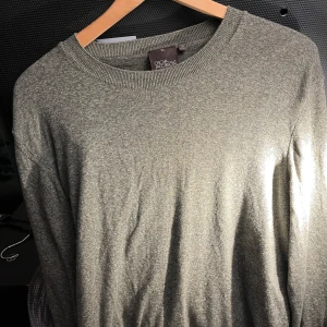 Grönmelerad tröja från Oscar Jacobson - Säljer en stilren grönmelerad tröja från Oscar Jacobson, tillverkad i Italien. Tröjan har en klassisk rund hals och långa ärmar, perfekt för en elegant och avslappnad look.