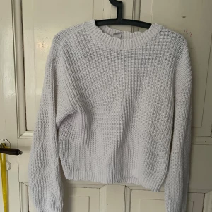 Vit stickad tröja - Säljer en vit stickad tröja med rund hals och långa ärmar. Perfekt för kyligare dagar och enkel att matcha med olika outfits. Tröjan har en klassisk design och är både stilren och bekväm.