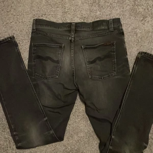 Svarta Nudie Jeans - Svart nudie jeans i skick 9/10. Ända defekten är en lite vit fläck på gylfen. Storlek 31/34. Skriv om ni har frågor.💯❗️Vid snabba affär kan jag gå ner lite i pris❗️