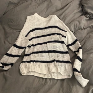 Vit och svart randig stickad tröja från 157 - Säljer en snygg vit stickad tröja från 157 med svarta ränder. Tröjan har en avslappnad passform och långa ärmar, perfekt för kyligare dagar. Den är både stilren och bekväm. Nästan aldrig använd. Köparen står för frakten.