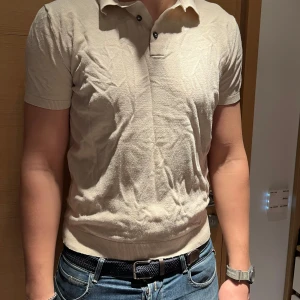 Beige pikétröja från Zara - Säljer en stilren beige pikétröja från Zara. Tröjan har korta ärmar och en klassisk krage med knappar. Perfekt för en avslappnad men ändå snygg look. Passar bra till jeans eller chinos.