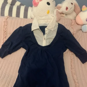 Mörkblå t-shirt med skjortdetalj från Friendtex - Snygg mörkblå t-shirt från Friendtex med en inbyggd vit skjortdetalj som har glittriga guldiga ränder. Stretchigt tyg så passar både, L, M och lite löst på en S. Själv thriftad på vintage lik loppis 