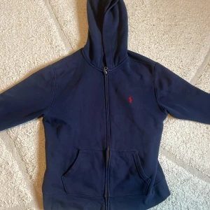 Blå Ralph lauren hoodie - Säljer nu min blåa ralph lauren hoodie med den ikoniska röd broderade hästen på då den blivit för liten. Hoodien är i storlek 14-16 år.