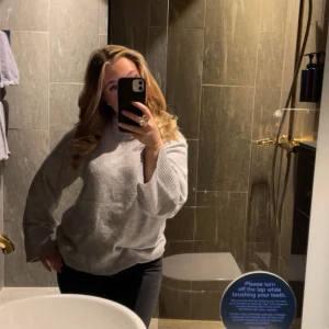 Grå stickad tröja - Mysig grå stickad tröja med långärmad design. Perfekt för kyligare dagar och ger en avslappnad stil. Passar bra till jeans eller kjol.