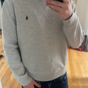 Grå tröja från Ralph Lauren  - Säljer en stilren grå tröja från Ralph Lauren med det klassiska logotypbroderiet på bröstet. Tröjan har långa ärmar. Perfekt för en avslappnad och snygg look.