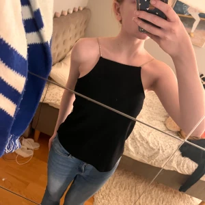 Svart ärmlös topp - Säljer en enkel svart ärmlös topp från H&M med tunna axelband i strass. Funkar både i vardagen eller till fest! Nypris: 179kr