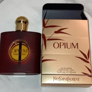 Opium Eau de Parfum från Yves Saint Laurent - Säljer en elegant flaska av Opium Eau de Parfum från Yves Saint Laurent. Flaskan är i en djup röd färg med en gyllene kork och detaljer. Doften är känd för sin intensiva och sensuella karaktär. Perfekt för den som vill ha en tidlös och sofistikerad parfym.