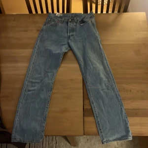 Blå jeansbyxor från Levis - Snygga blå jeansbyxor från Levis med klassisk femficksdesign. De har en straight passform och är perfekta för en avslappnad stil. Byxorna har en knappgylf och är tillverkade i slitstarkt denim. Inga fläckar eller håll i byxorna 