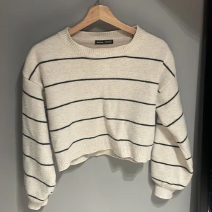 Beige/vit randig tröja från Shein - Säljer en beige randig tröja från Shein. Tröjan är croppad med långa ärmar och har ett klassiskt randigt mönster i svart. Perfekt för en avslappnad stil.