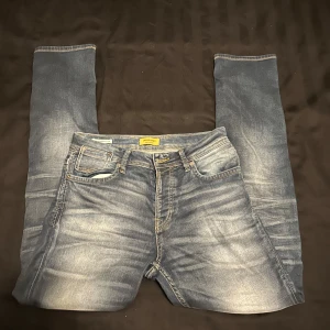 Blå jeans från Jack & Jones - Snygga blå jeans från Jack & Jones med en klassisk femficksdesign. De har en lätt tvättad look och är perfekta för en avslappnad stil. Jeansen har en dragkedja och knapp framtill. Kontakta vid frågor och funderingar!