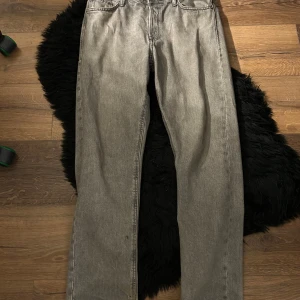 Grå jeans från Jack & Jones - Snygga grå jeans från Jack & Jones med klassisk design. De har en rak passform och är perfekta för en avslappnad stil. Jeansen har en knappgylf och är tillverkade i ett slitstarkt material.