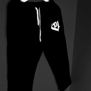 Svarta mjuksbyxor med vit logo - Snygga svarta mjukisbyxor med en vit broderad logga på benet. Byxorna har en bekväm passform med snörning i midjan för justerbarhet. Perfekta för en avslappnad stil och för finare tillfällen.  350Gsm och chenille embrodery! Aldrig använda! 