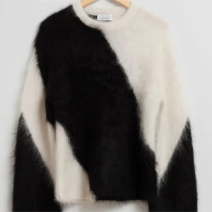 Svart och vit fluffig tröja från other stories  - Säljer en unik och stilren svart och vit tröja från & other stories. Tröjan är fluffig och har ett diagonalt mönster som ger en cool look. Perfekt för att hålla sig varm och trendig under kyliga dagar.