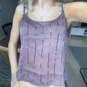 Lila ärmlös topp med pärldetaljer - Snygg lila ärmlös topp med pärldetaljer och knappar på baksidan. Säljer då den inte kommer till användning längre men i jätte bra skick!