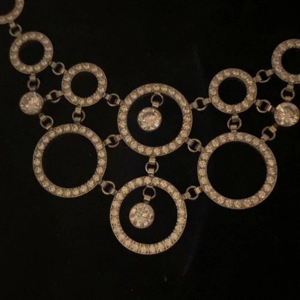 Elegant halsband från Edblad med en unik cirkeldesign. Halsbandet består av flera sammanlänkade cirklar dekorerade med glittrande stenar, vilket ger en lyxig känsla. Perfekt för att lyfta vilken outfit som helst. Aldrig använd, kommer med låda 🩵. Asusteet.