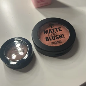 W7 Matte Me Blush och Sandstone Ögonskugga - Säljer en W7 Matte Me Blush i en härlig persikofärg och en Sandstone ögonskugga i en varm brun nyans. Perfekt för att skapa en naturlig look med en matt finish. Blushen ger en mjuk färg till kinderna medan ögonskuggan framhäver ögonen.