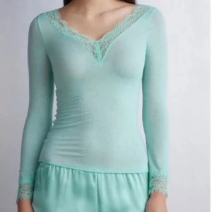 Turkos långärmad topp från Intimissimi - Säljer en turkos topp från Intimissimi med vacker spetsdetalj vid halsringningen och ärmsluten. Toppen är långärmad och har en v-ringad design. Endast använd några gånger och slutsåld på hemsidan.