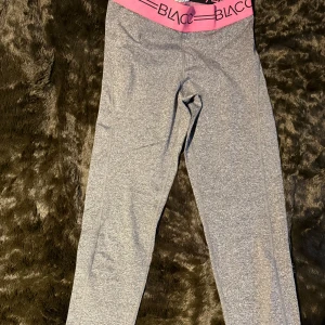 Grå leggings från Blacc - Snygga grå leggings från Blacc med en bred rosa resår i midjan. Perfekta för träning eller en avslappnad dag. Materialet är mjukt och stretchigt för bästa komfort.