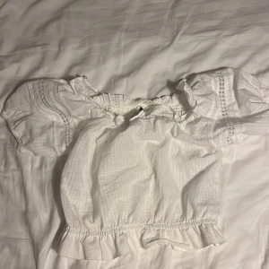 Vit blus med volangdetaljer🤍 - Vit topp med korta puffärmar och volangdetaljer vid ärmslut och nederkant. Blusen har en elastisk halsringning och fina spetsdetaljer på ärmarna. Använd fåtal gånger❣️