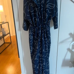 Mörkblå mönstrad jumpsuit från Monki - Snygg mörkblå jumpsuit med skjortkrage, trekvartsärmar och en dragsko i midjan för en smickrande passform. Perfekt för en stilren look.