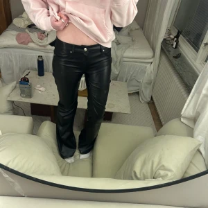 Svarta skinnbyxor - Snygga svarta skinnbyxor med bootcut-stil. Byxorna har en lågmidjad passform och är perfekta för en trendig look. De har knappar och dragkedja framtill. Storlek 40 men eftersom dem insydda skulle jag uppskatta storleken till en 34/36. Visas på mig som är 175