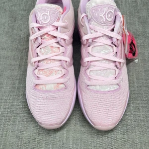 Nike KD15 Aunt Pearl  - Snygga rosa sneakers med unik mönstrad sula och snörning. Skorna har en stilren design med detaljer i olika rosa nyanser och ett märke på plösen. Perfekta för en sportig look.