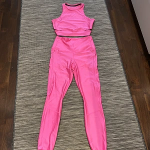 Rosa träningskläder från Nike - Säljer en snygg rosa träningstopp från Nike. Toppen är ärmlös och har en tight passform, perfekt för träning. Den är gjord i ett mjukt och stretchigt material som ger bra rörelsefrihet.