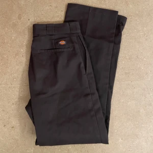 Gråa byxor från Dickies - Snygga gråa Dickies 874 byxor med klassisk design. De har en rak passform och är tillverkade i slitstarkt material. Perfekta för en stilren look. Säljes då jag inte använder byxorna längre!