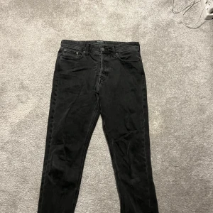 Svarta jeans Jack & Jones LOOSE/CHRIS - Snygga svarta jeans med klassisk femficksdesign och knappgylf. Perfekta för en stilren look. Storlek 31-32.