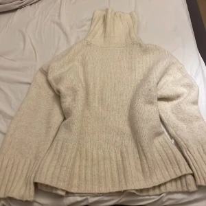 Vit stickad polotröja  - Mysig vit stickad polotröja från H&M med ribbade detaljer och slit längst ner på båda sidorna. Tjock och varm stickad