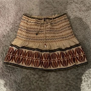 Beige kjol med mönster - Charmig beige kjol med elastisk midja och knytband. Kjolen sälj inte längre helt okej skick, Fårn Zara.