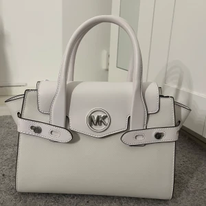Vit handväska från Michael Kors - Snygg vit handväska från Michael Kors. Väskan har två handtag och en praktisk dragkedja inuti.