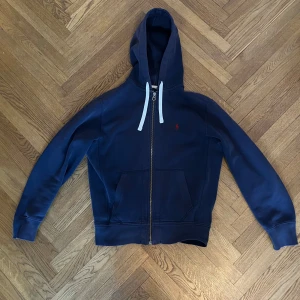 Polo Ralph Lauren Zip Hoodie - Skick är som på bilderna. Lite urtvättad färg men annars i bra skick.  Hör av er vid ytterligare frågor!