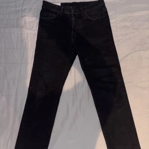 Svarta jeansbyxor - Snygga svarta jeansbyxor med en klassisk design. De har en midwaist passform och är perfekta för en stilren look. Byxorna har en dragkedja och knappar framtill.