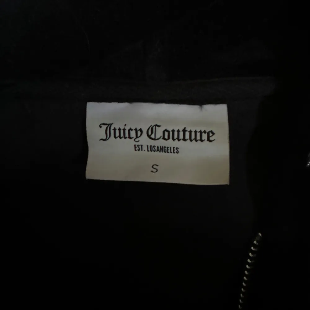 Säljer en supermjuk och snygg svart velourjacka från Juicy Couture. Den har en dragkedja framtill och en huva med snörning. På baksidan finns det ikoniska Juicy Couture-loggan i glittriga stenar. . Takit.
