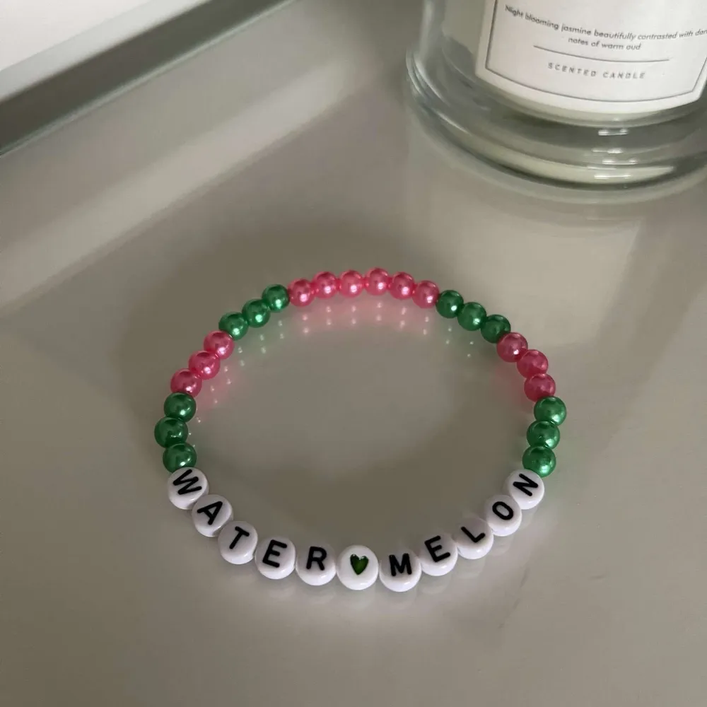 Säljer ett supergulligt armband med pärlor i rosa och grönt, perfekt för sommarens alla äventyr! Armbandet har vita bokstavspärlor som bildar ordet 'WATERMELON' med ett litet grönt hjärta i mitten. Det är elastiskt och passar de flesta handleder. Perfekt för att ge en färgklick till din outfit!. Accessoarer.