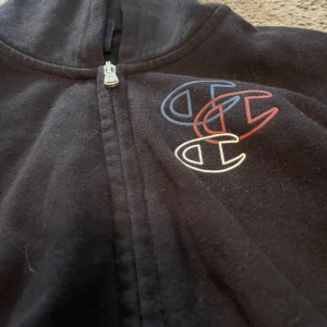 Svart huvtröja från Champion - Säljer två styckna svarta huvtröjor från Champion i storlek XL och L. Den har Champion-loggan broderad på bröstet och ärmen. Perfekt för en avslappnad stil! Använda ett par ggr. 2 för 70, en för 40.