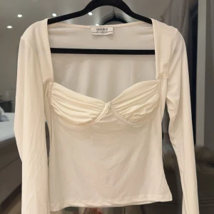 Vit långärmad topp från Chiquelle - Säljer en superfin vit långärmad topp från Chiquelle. Den har en snygg twist-detalj vid bysten som ger en unik look. Perfekt för både vardag och fest!