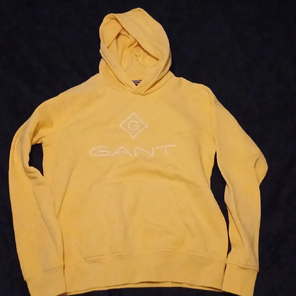 Säljer en snygg gul hoodie från GANT. Den är i bra skick. Perfekt för höst och vår, och den är superbekväm med långa ärmar och en mysig luva . Passar perfekt för en avslappnad stil!. Tröjor & Koftor.