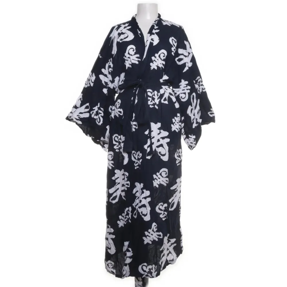 Säljer en superfin mörkblå kimono med ett coolt vitt mönster. Den har en lång och flödande design med vida ärmar och ett knytband i midjan. Perfekt för en avslappnad dag hemma eller som en statement-piece på festen!. Klänningar.