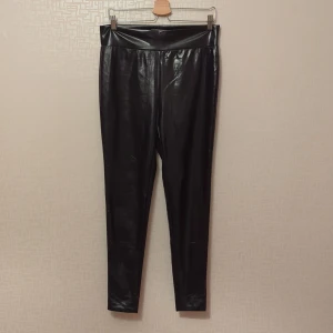 Svarta leggings från Bik Bok - Säljer ett par svarta leggings från Bik Bok i storlek XL. De är gjorda i ett glansigt material som ger en cool look. Perfekta för både vardag och fest! Stretchiga på bredden men inte på längden, innermått ben 70cm. Hely nya.