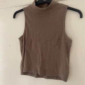 Beige ärmlös polotopp från Vero Moda - Säljer en snygg beige ärmlös polotopp från Vero Moda. Den är ribbad och har en tight passform, perfekt för både vardag och fest. Toppen är i nyskick och superbekväm att ha på sig!