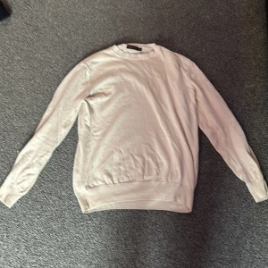 Beige tröja från Oscar Jacobson - Säljer en stilren beige tröja från Oscar Jacobson. Tröjan har en klassisk rund hals och långa ärmar, perfekt för en elegant och avslappnad look. Passar bra till både vardag och mer uppklädda tillfällen.