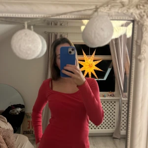 Röd långärmad topp - Säljer en snygg röd långärmad topp med rund halsringning. Perfekt för att lägga till en färgklick i garderoben. Passar bra till både jeans och kjol.